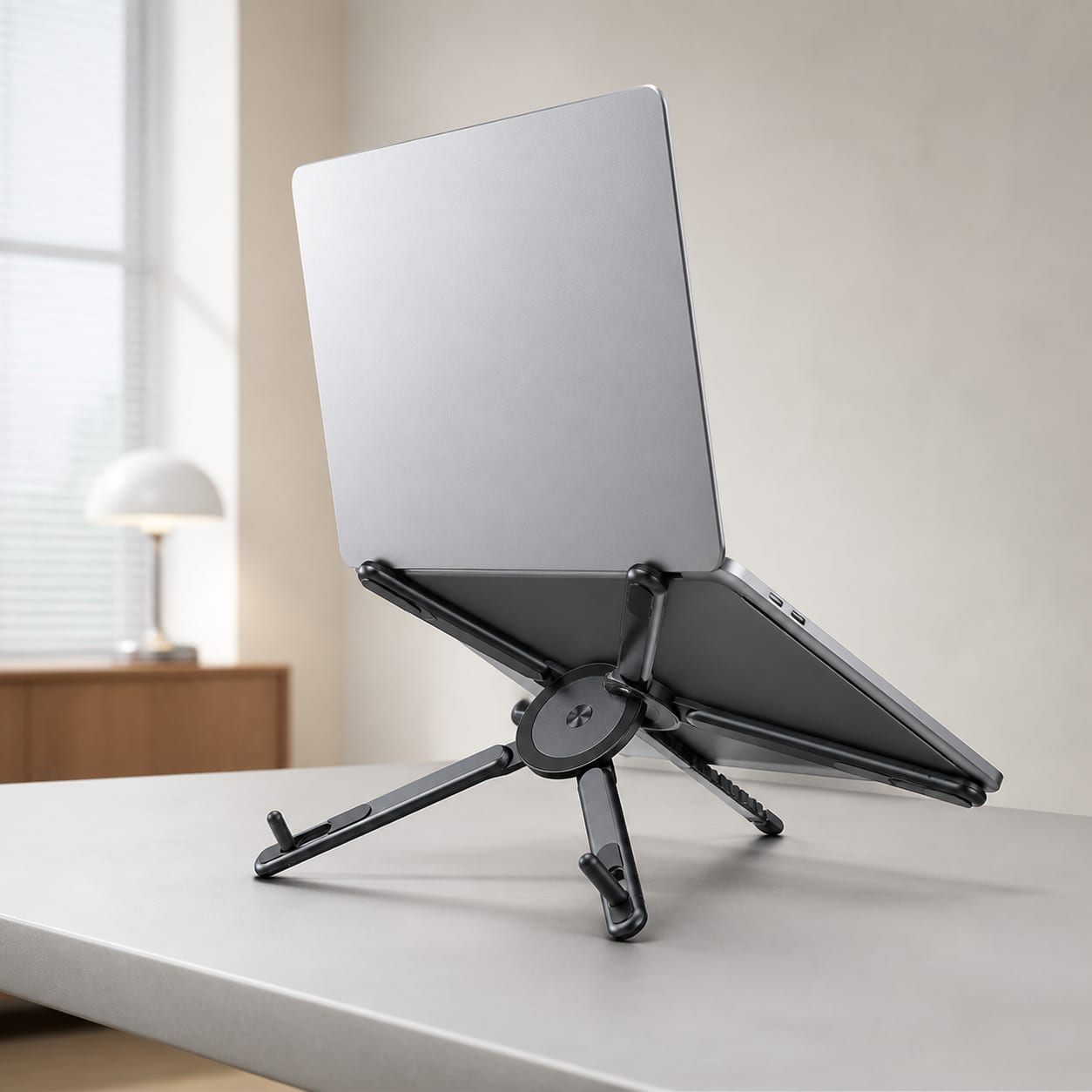 Graphite MagFold adjustable device stand supporting a laptop in a bright home office.