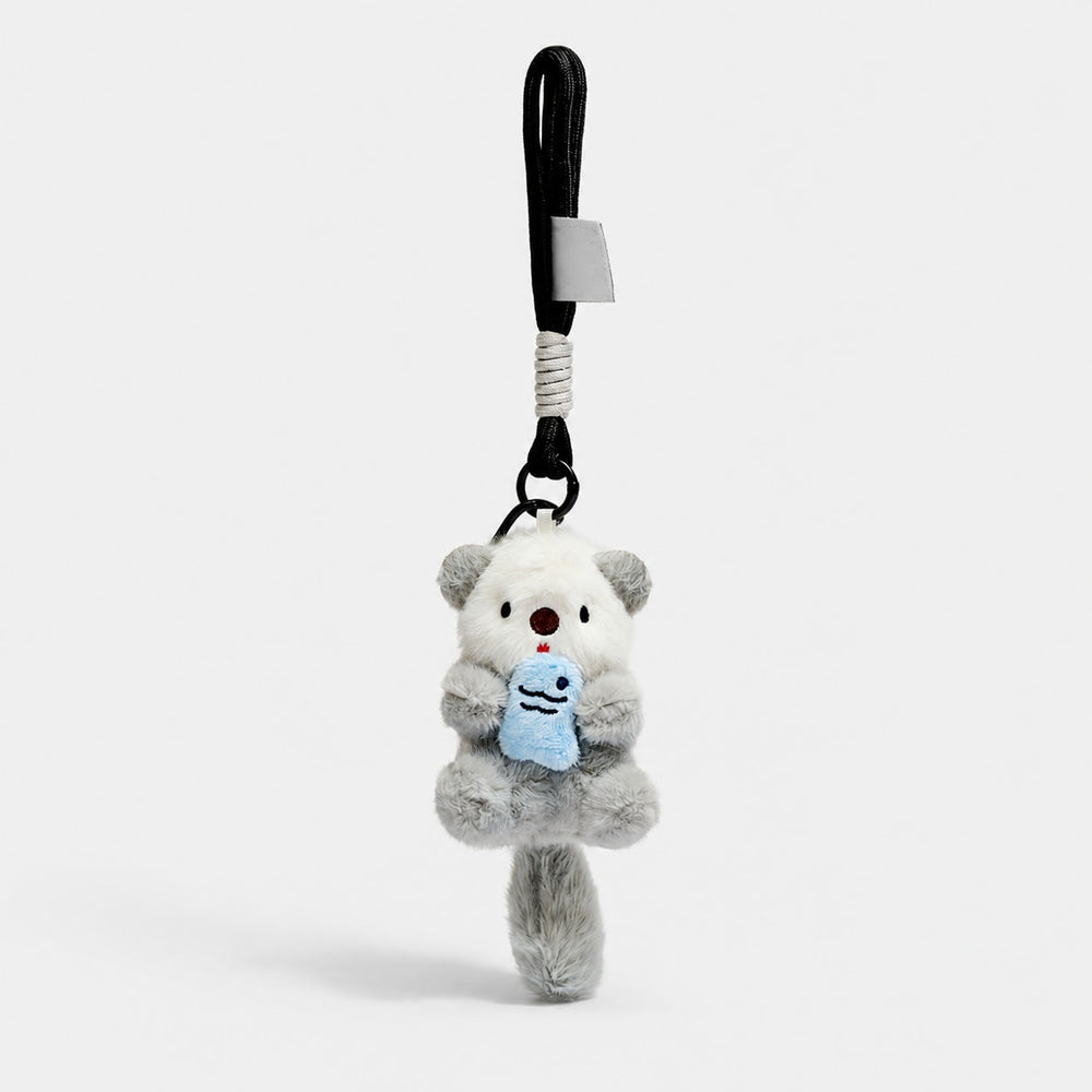 Gray otter plush bag charm holding a blue fish, with a black rope wrist loop.