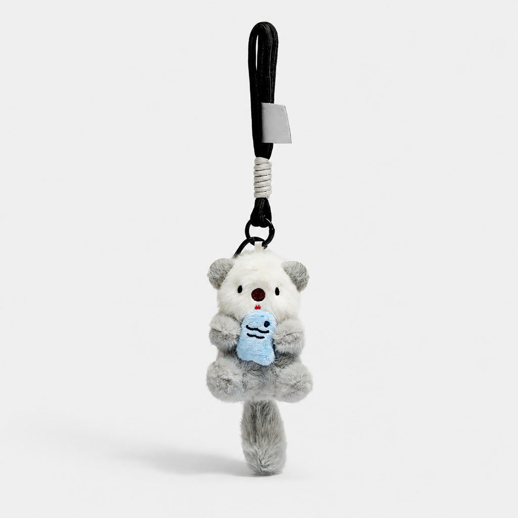 Gray otter plush bag charm holding a blue fish, with a black rope wrist loop.