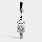 Gray otter plush bag charm holding a blue fish, with a black rope wrist loop.