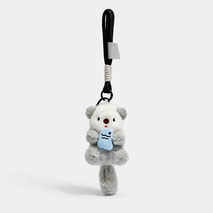 Gray otter plush bag charm holding a blue fish, with a black rope wrist loop.