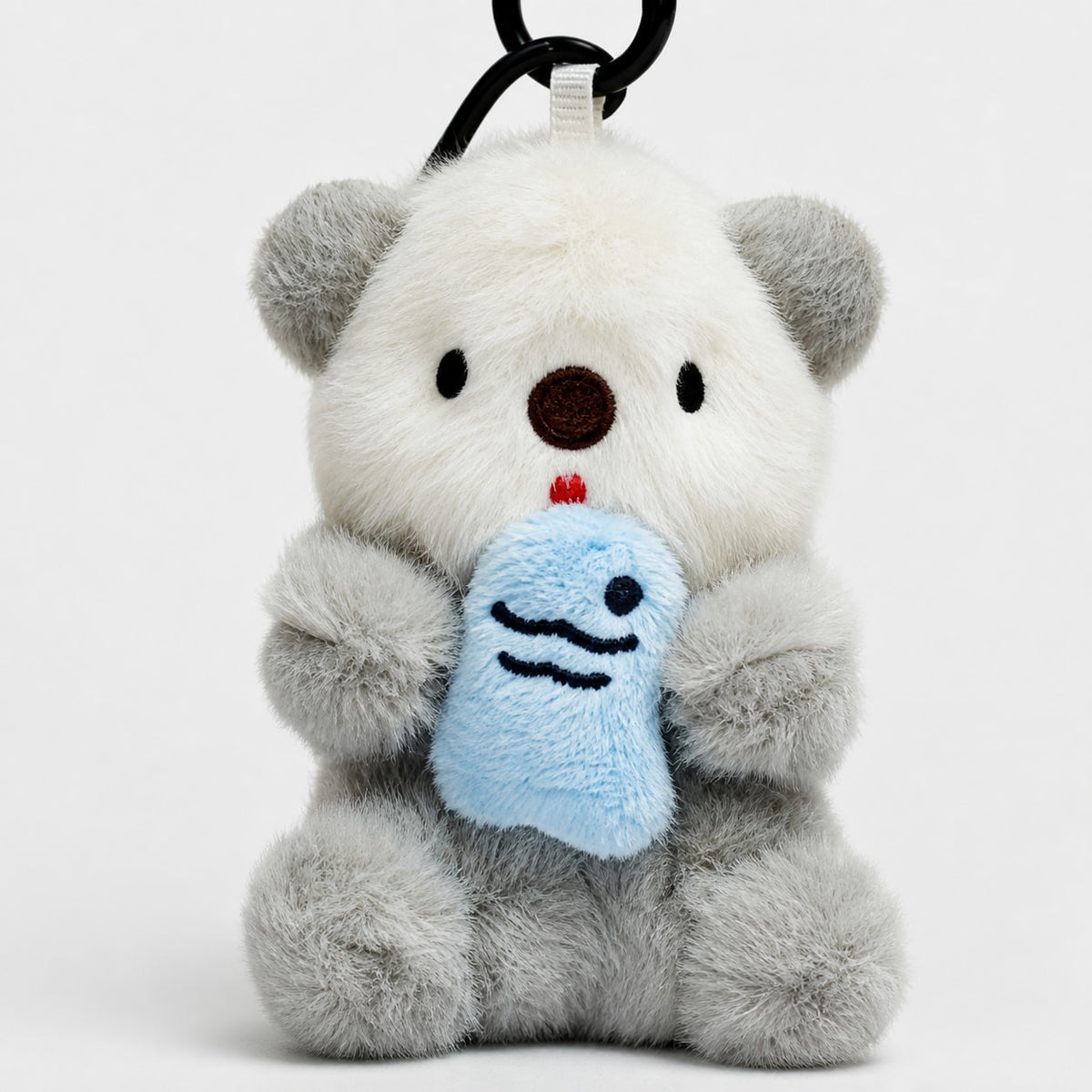 Close-up of the gray otter bag charm's plush face, blue fish and textured fabric.